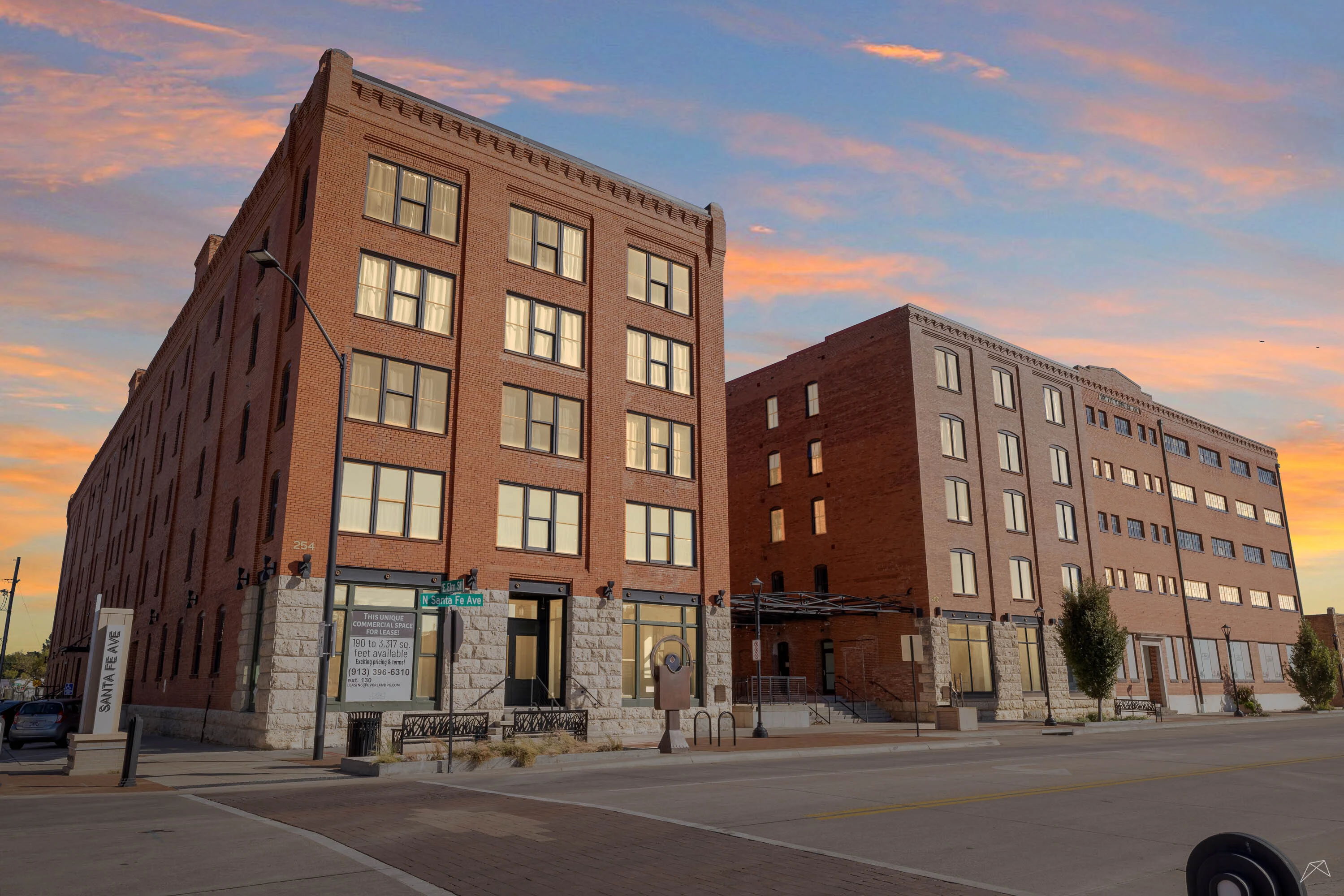 A pair of multistory brick buildings at sunset, blending historic and modern styles, evoke warmth, nostalgia, and community.
