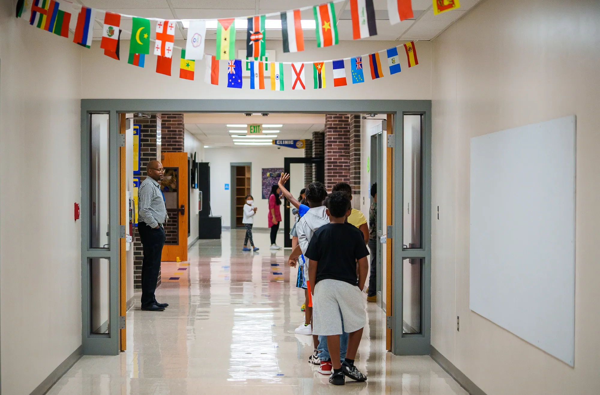 Children walk in a colorful school hallway decorated with flags, exuding joy, curiosity, and a sense of community.