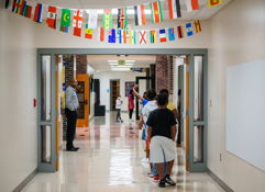 Children walk in a colorful school hallway decorated with flags, exuding joy, curiosity, and a sense of community.