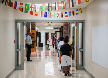Children walk in a colorful school hallway decorated with flags, exuding joy, curiosity, and a sense of community.