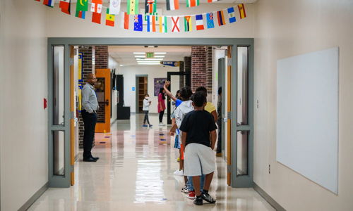 Children walk in a colorful school hallway decorated with flags, exuding joy, curiosity, and a sense of community.