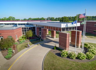 A modern building with flags, lush gardens, and a sunny sky evokes optimism and community warmth.