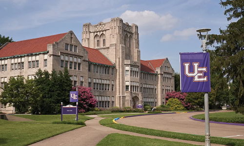 Charming college campus with a grand building, lush greenery, and a welcoming atmosphere of learning and growth.