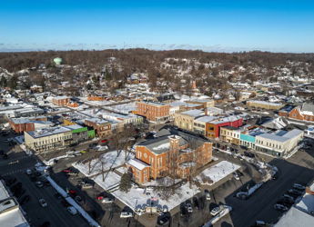 Aerial view of a snow-covered small town, featuring colorful buildings and serene winter landscapes, evoking charm and nostalgia.