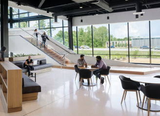 Modern open space with large windows, minimalistic furniture, and diverse groups engaged in conversation, conveying collaboration.