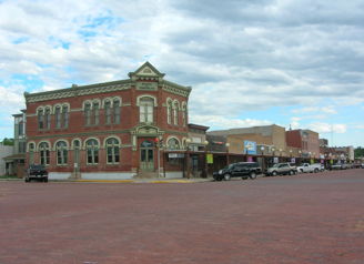 Charming historic street scene with a brick building, storefronts, parked cars, and a nostalgic, serene atmosphere.