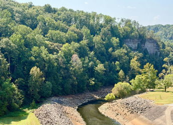 A tranquil landscape with a winding river, lush trees, and rocky cliffs evokes serenity and a connection to nature.