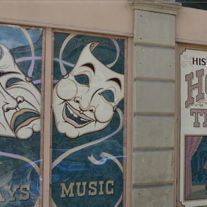 The image shows a classic theater exterior with vibrant signage and masks of comedy and tragedy, evoking nostalgia and excitement.
