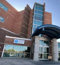 Modern medical facility with glass windows, blue awning, and brick exterior, evoking professionalism and reassurance.
