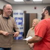 Three smiling people converse in a relaxed, professional setting, radiating joy and camaraderie.