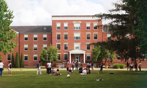 A lively outdoor scene near a brick building, with children and young adults playing and socializing in a cheerful atmosphere.