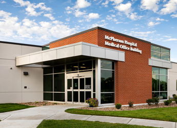 Modern medical building with brick and glass architecture, bright sky, and inviting landscape, evoking safety and care.
