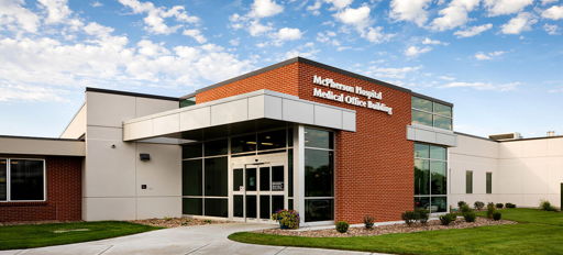 Modern medical building with brick and glass architecture, bright sky, and inviting landscape, evoking safety and care.
