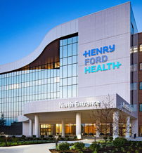 A modern health facility with glass windows and a brick facade, conveying hope and calmness in a serene setting.