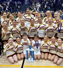 Cheerleaders joyfully pose together in matching uniforms, celebrating a competition victory with trophies and medals.