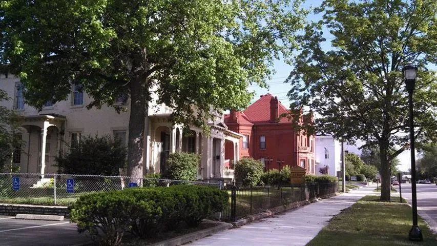 A serene residential street with varied houses, lush greenery, and a sunny atmosphere evokes feelings of warmth and community.