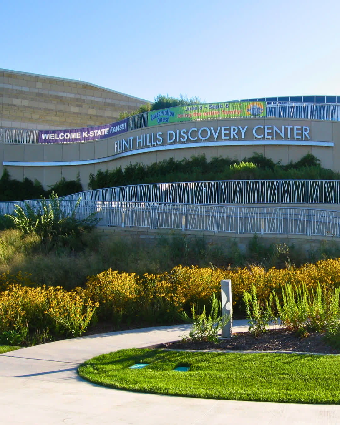 Flint Hills Discovery Center with modern design, vibrant flowers, and welcoming pathway, evokes curiosity and community engagement.