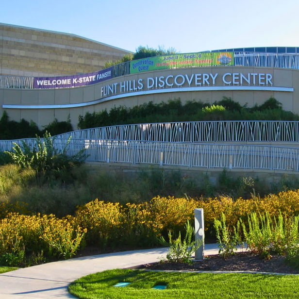 Flint Hills Discovery Center with modern design, vibrant flowers, and welcoming pathway, evokes curiosity and community engagement.