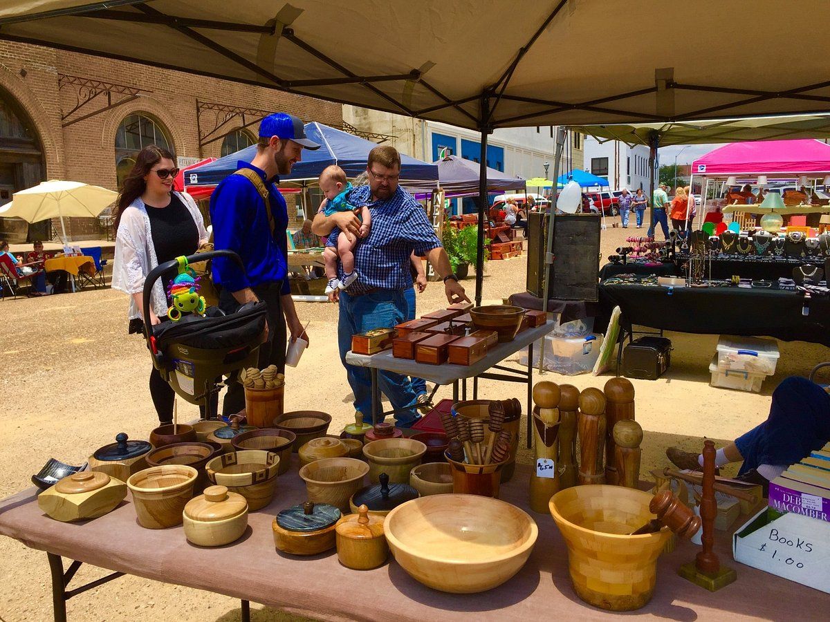 Outdoor market scene with vibrant handmade wooden items, a vendor, and families, evoking warmth and community.