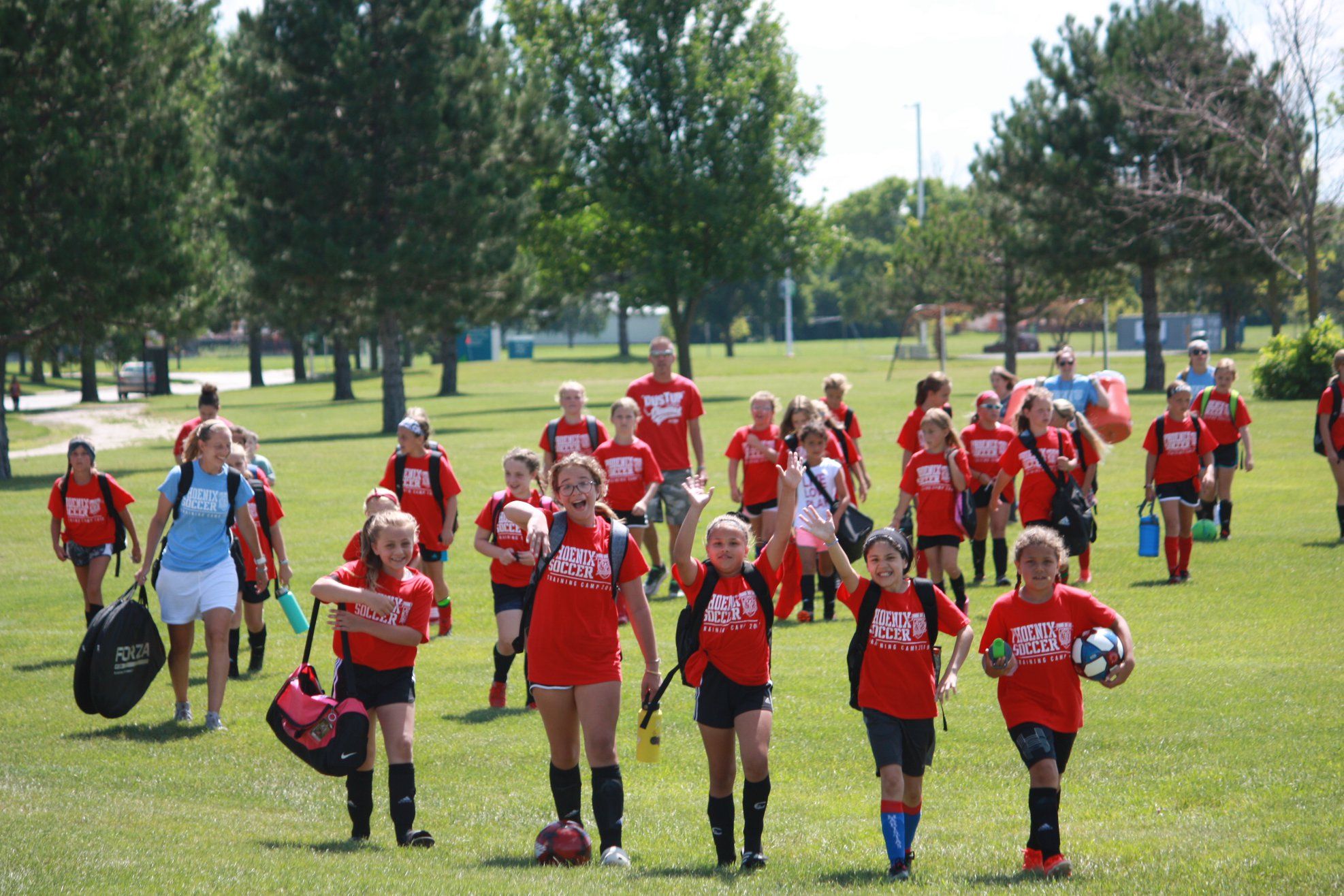 Young girls in matching red shirts heading to soccer practice, showcasing teamwork, joy, and a vibrant outdoor setting.
