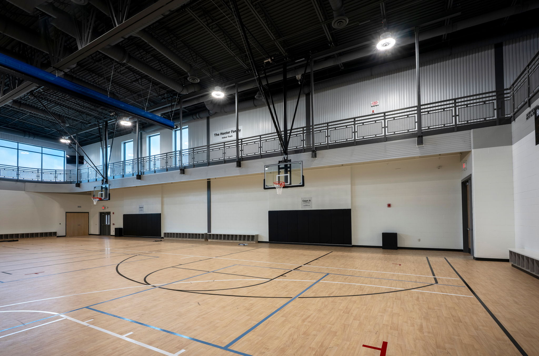 Empty gymnasium with polished wood floor, basketball hoop, and bright natural light; evokes anticipation and possibility.