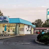 Quaint ice cream shop "Frost Bite" with a turquoise roof, outdoor seating, and a cheerful, inviting atmosphere.