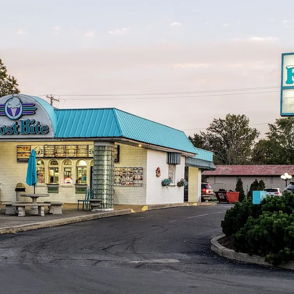 Quaint ice cream shop "Frost Bite" with a turquoise roof, outdoor seating, and a cheerful, inviting atmosphere.