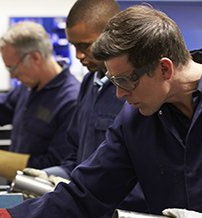 Three workers in a technical workshop, focused and safe, embodying diligence, teamwork, and pride in craftsmanship.