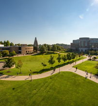 A sunny campus scene with green lawns, modern buildings, and people walking, evoking joy and a sense of community.
