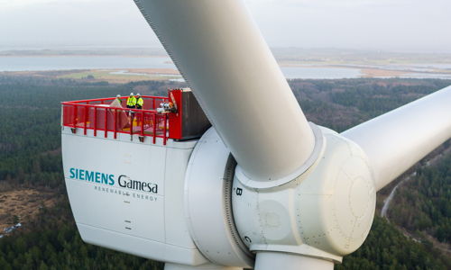 Wind turbine with workers on a service platform; symbolizes innovation, teamwork, and a connection to nature.