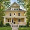 Classic yellow two-story house with a front porch, surrounded by greenery, evoking warmth, nostalgia, and tranquility.