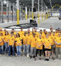 A united group in yellow shirts stands in a warehouse, exuding teamwork, positivity, and pride in their work.
