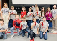 Children and adults celebrate achievements, smiling and holding red awards in a joyful, supportive community setting.