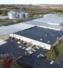 Industrial complex with flat-roof buildings, silos, greenery, and an organized parking lot, conveying productivity and balance.