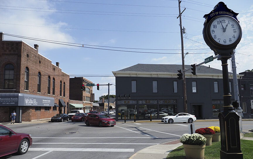 Charming small-town intersection with a vintage clock, blending old and modern architecture, flowers, and a vibrant community spirit.