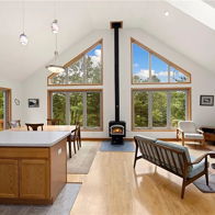 Bright, spacious living area with large windows, modern design, cozy seating, stylish wood stove, warm colors for comfort.
