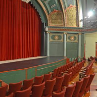 Classic theater interior with red curtain, inviting seating, and ornate decor, evoking excitement and nostalgia.