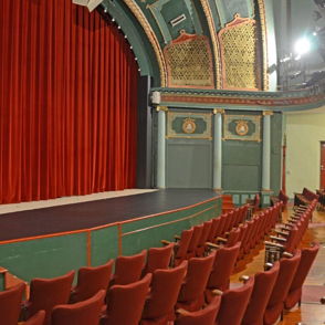 Classic theater interior with red curtain, inviting seating, and ornate decor, evoking excitement and nostalgia.