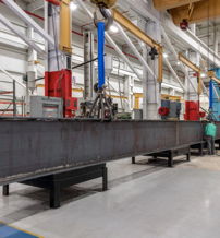 Industrial facility with large metal beams, cranes, and machinery; conveys productivity, efficiency, and teamwork.