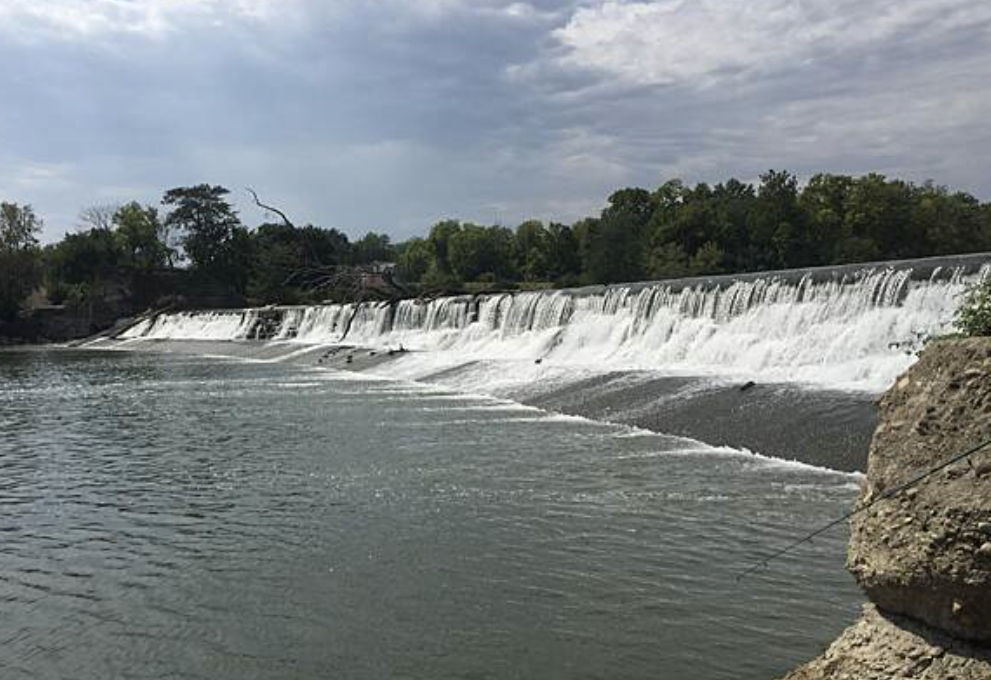 A serene landscape with a waterfall surrounded by greenery, evoking peace and relaxation under a partly cloudy sky.