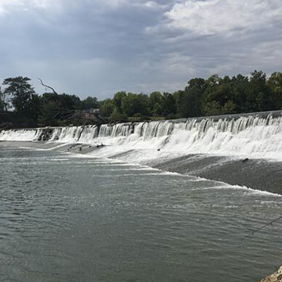 A serene landscape with a waterfall surrounded by greenery, evoking peace and relaxation under a partly cloudy sky.