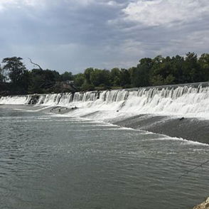 A serene landscape with a waterfall surrounded by greenery, evoking peace and relaxation under a partly cloudy sky.