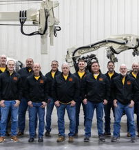 Group of men in matching black jackets with yellow accents stand confidently by large machinery, showcasing teamwork and professionalism.