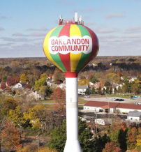 Colorful water tower with "OAKLANDON COMMUNITY" surrounded by autumn trees, evoking community, nostalgia, and a cozy atmosphere.