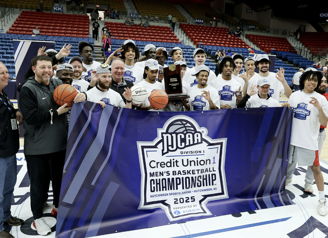 Basketball team celebrates NJCAA Championship victory with joy, holding a trophy and basketballs, showcasing teamwork and pride.