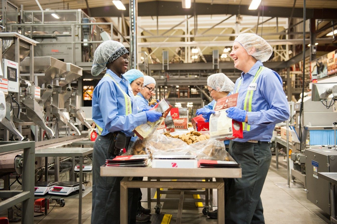 A collaborative team in blue uniforms works in a food processing facility, promoting hygiene and a positive, energetic atmosphere.