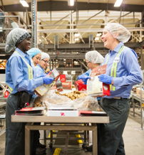 A collaborative team in blue uniforms works in a food processing facility, promoting hygiene and a positive, energetic atmosphere.