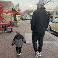 A father and child walk together on a charming street, evoking warmth, connection, and the joy of familial bonds.