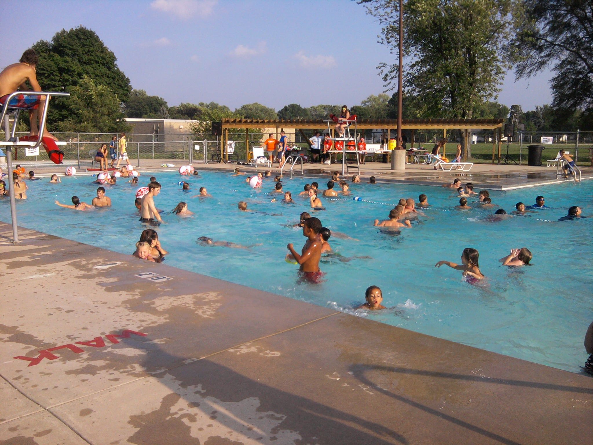 A vibrant pool scene with joyful people swimming and playing, capturing summer fun and community on a sunny day.