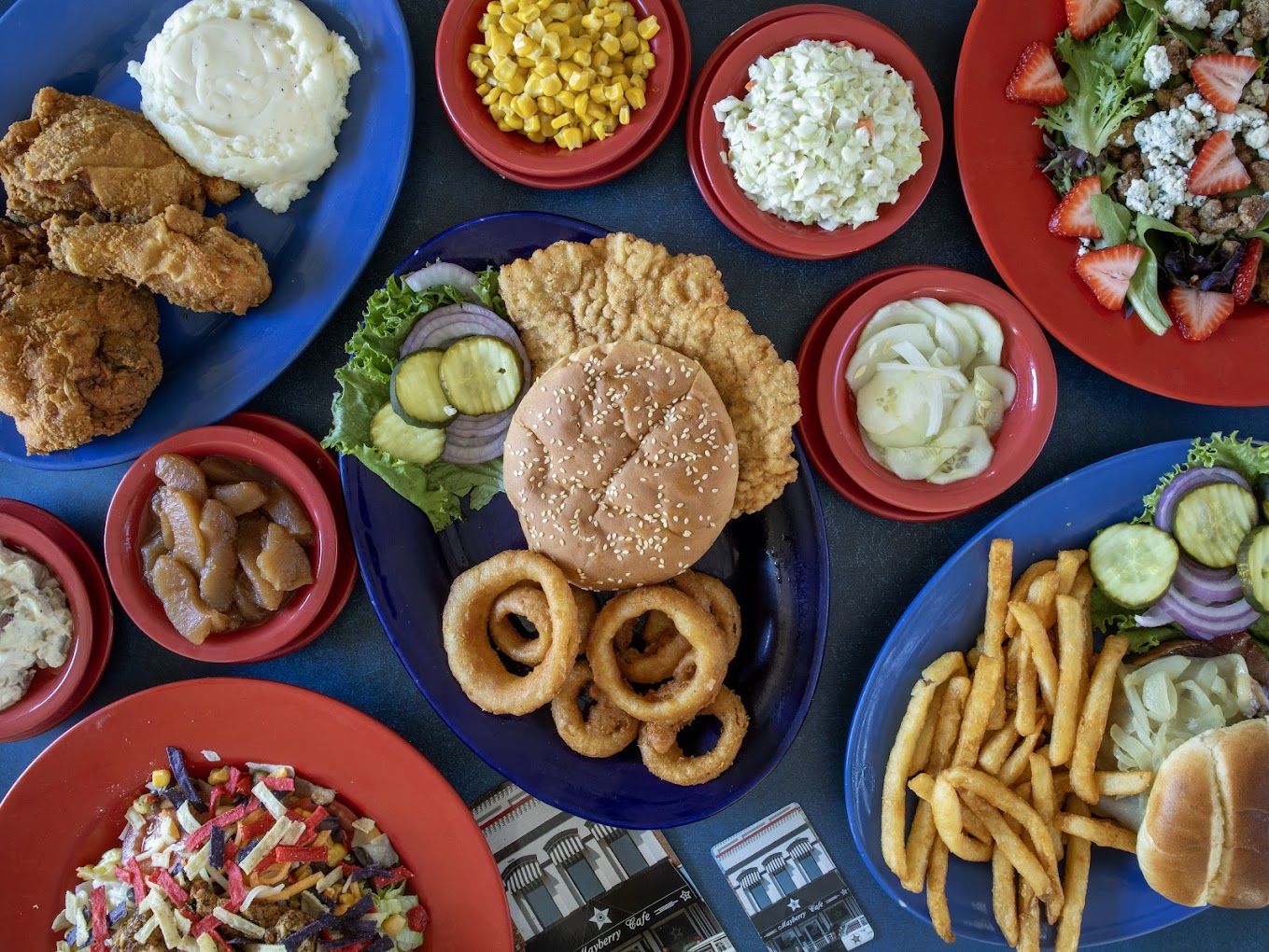A colorful spread of fried chicken, burgers, onion rings, fries, and sides evokes comfort and joy in a festive atmosphere.